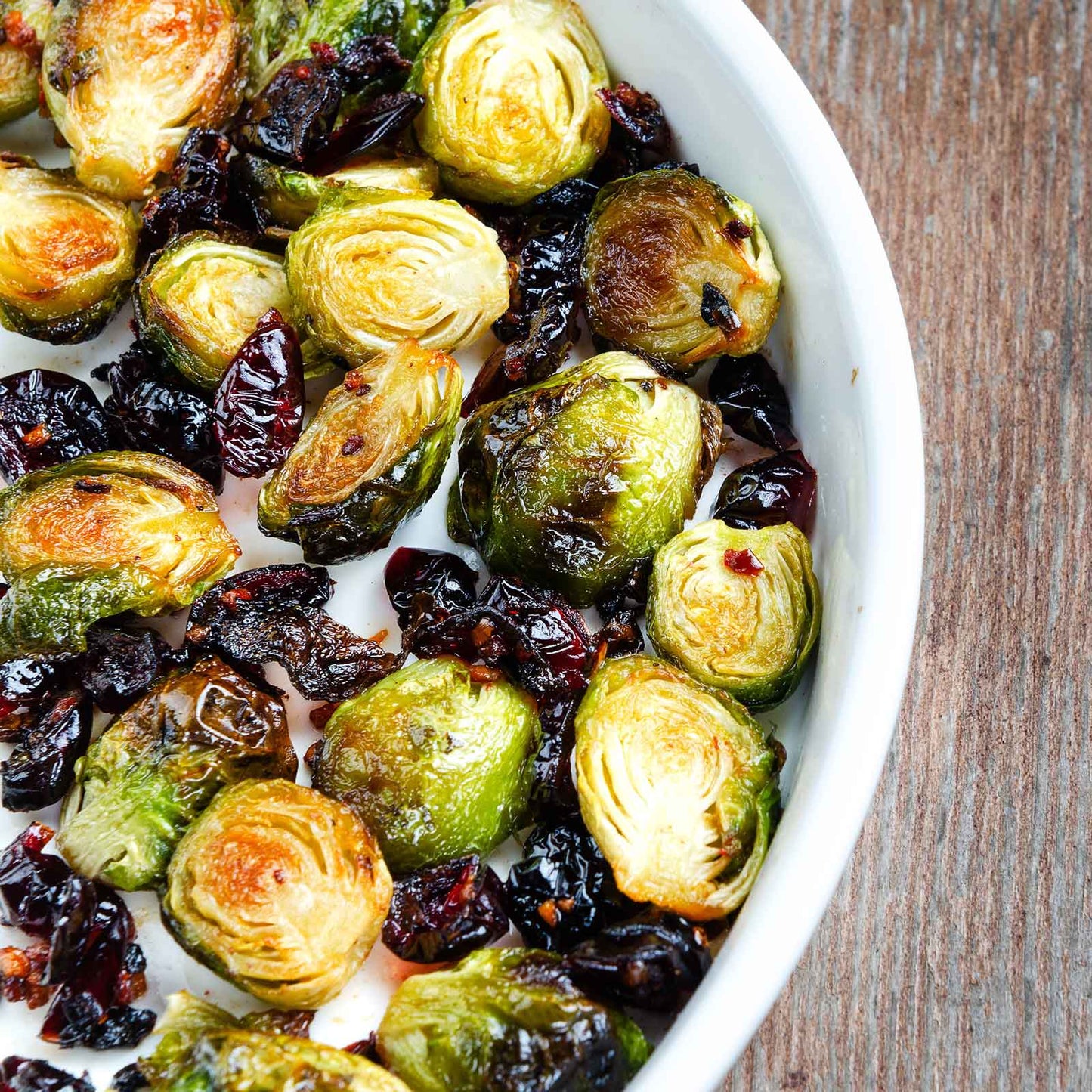 A bowl of roasted catskills brussels sprouts on a neutral background.
