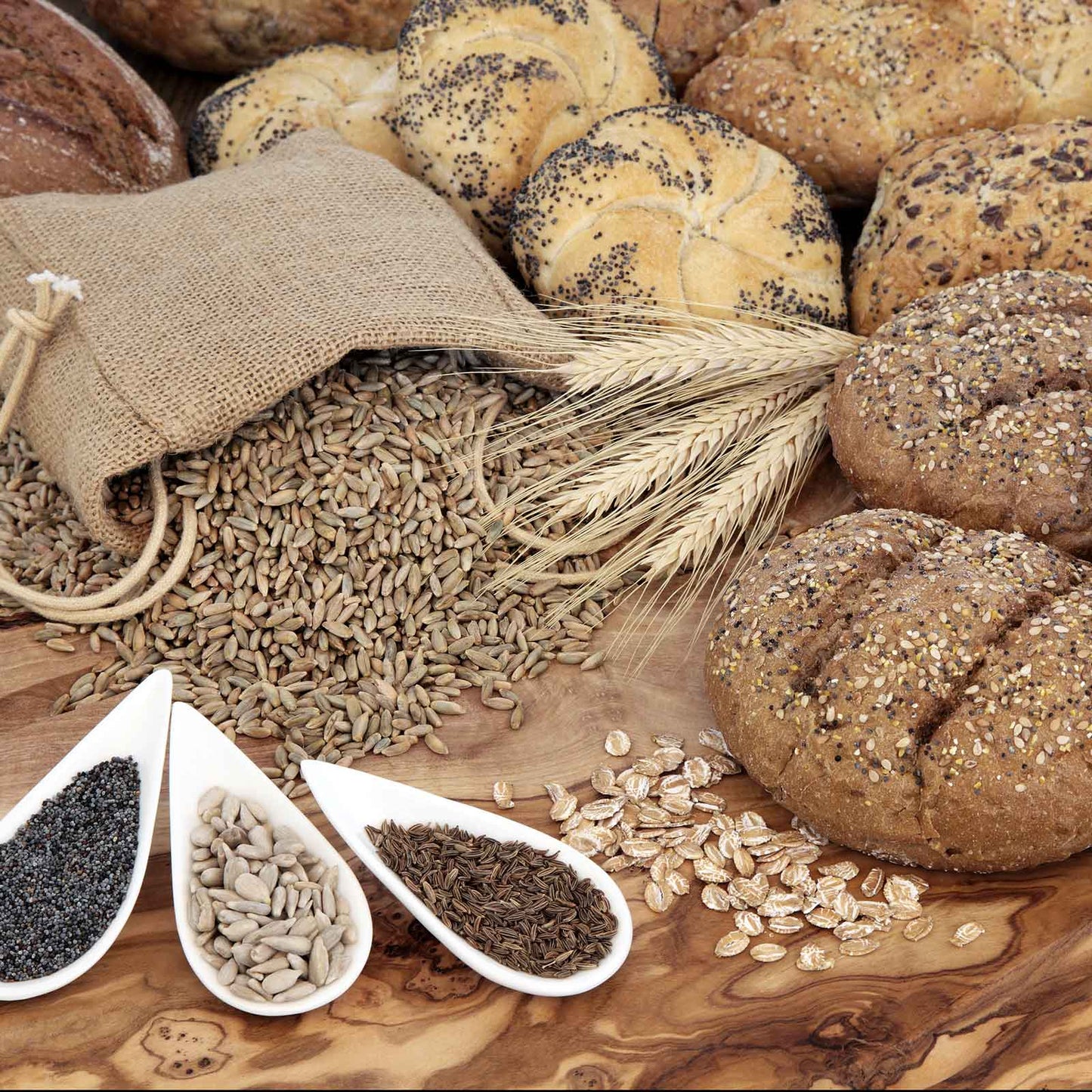 A close-up shot of caraway seeds, on the table, spilling out of a bag, and on bread.