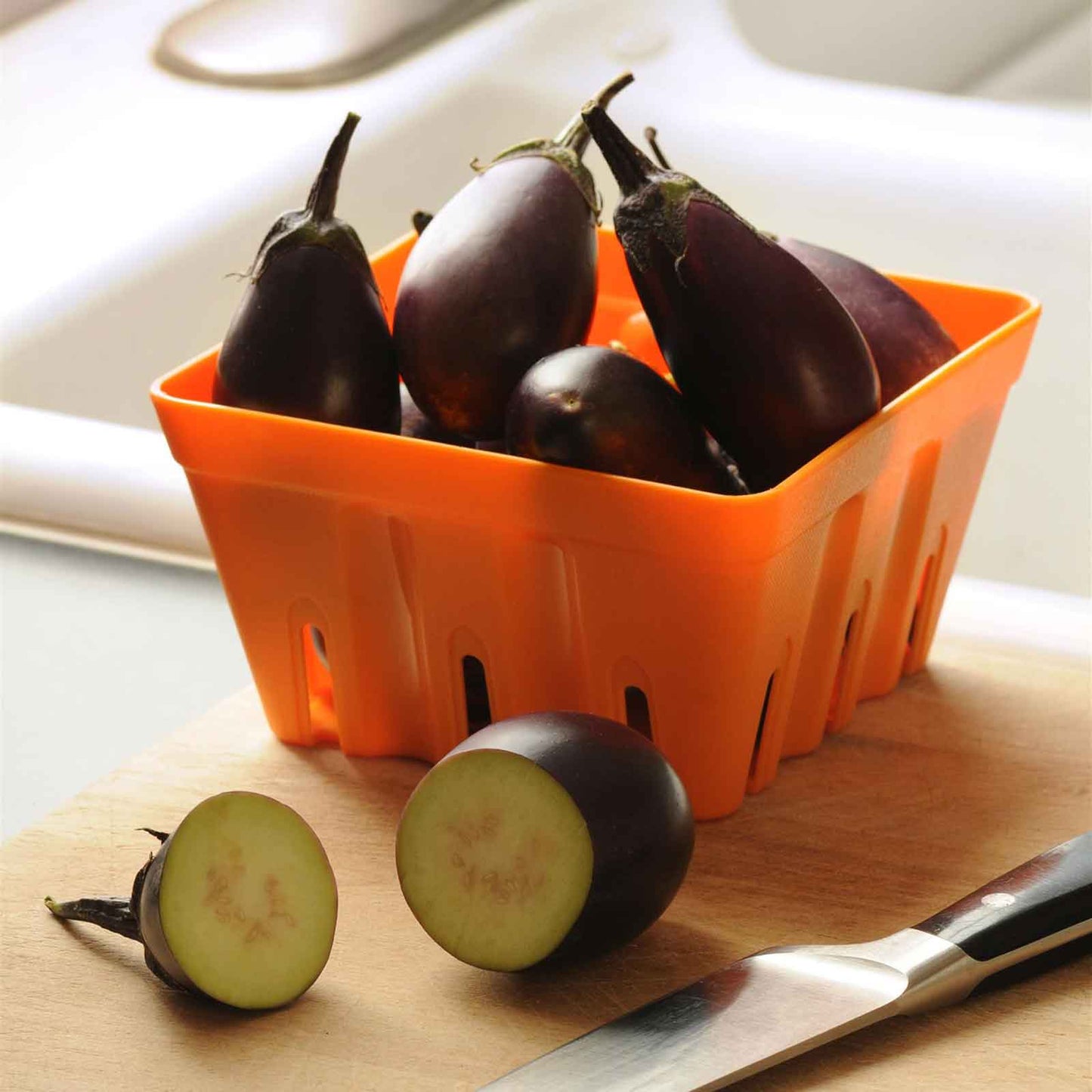 Harvested Patio Baby eggplants in an orange plastic container.