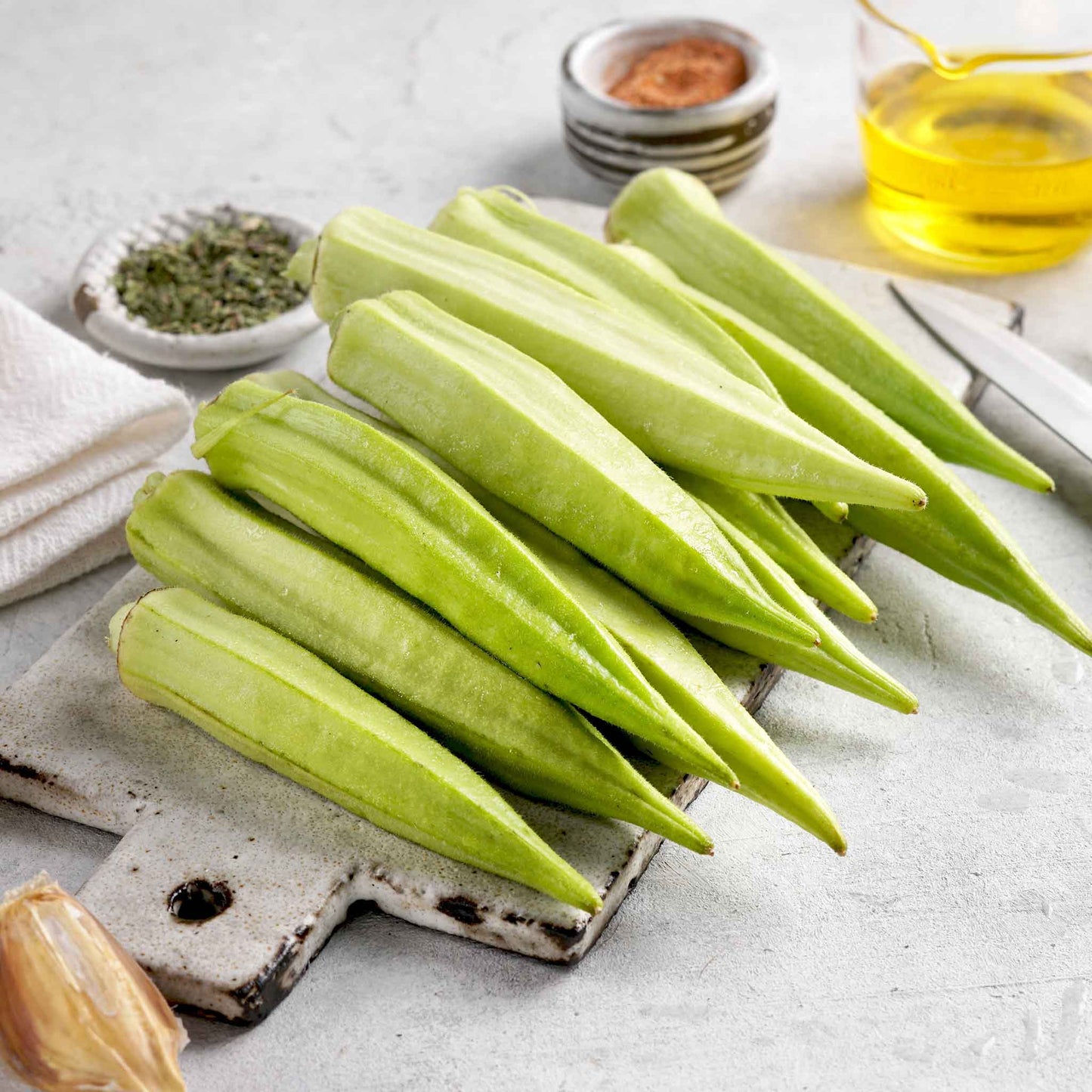 A close-up shot of several light green Blondy okra pods with ridged sides on a light surface.