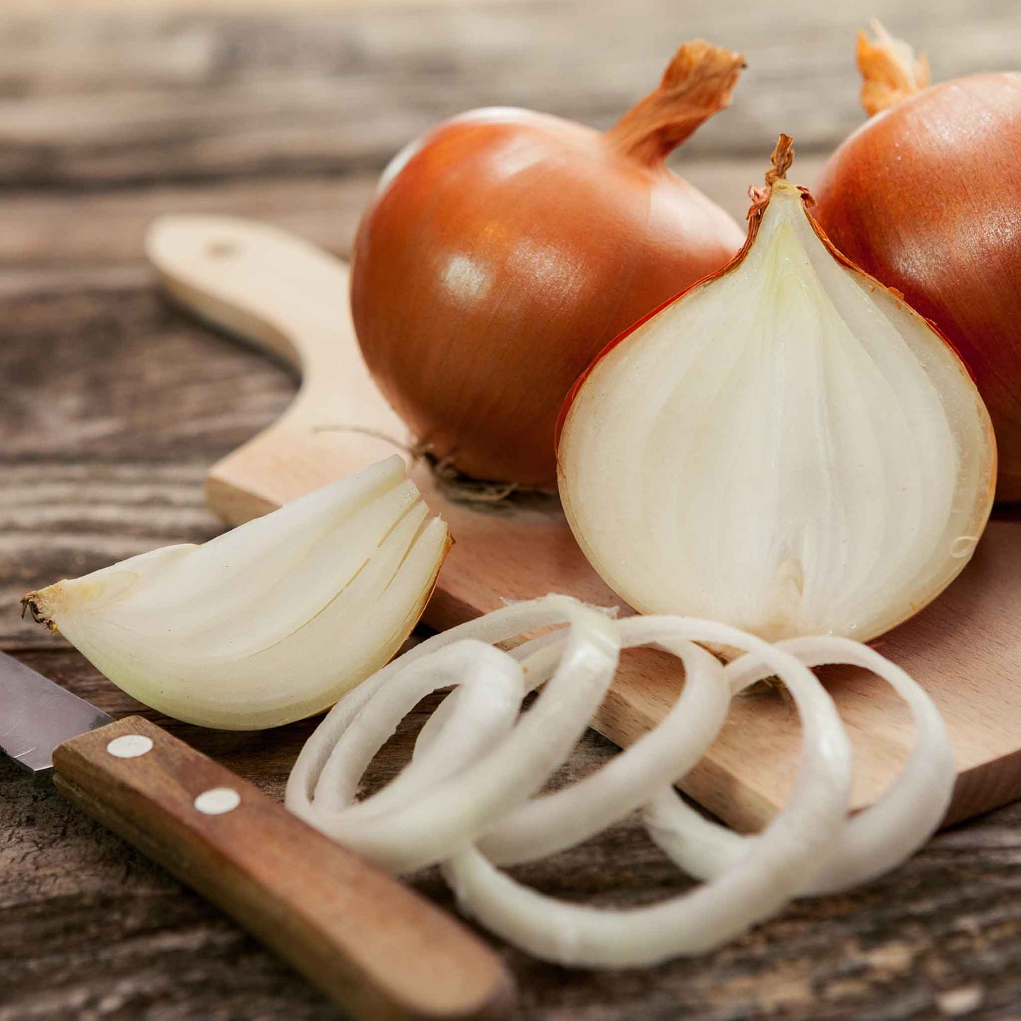 Close-up of a bunch of candy onions with thin, papery, golden-brown skins and sliced rings.