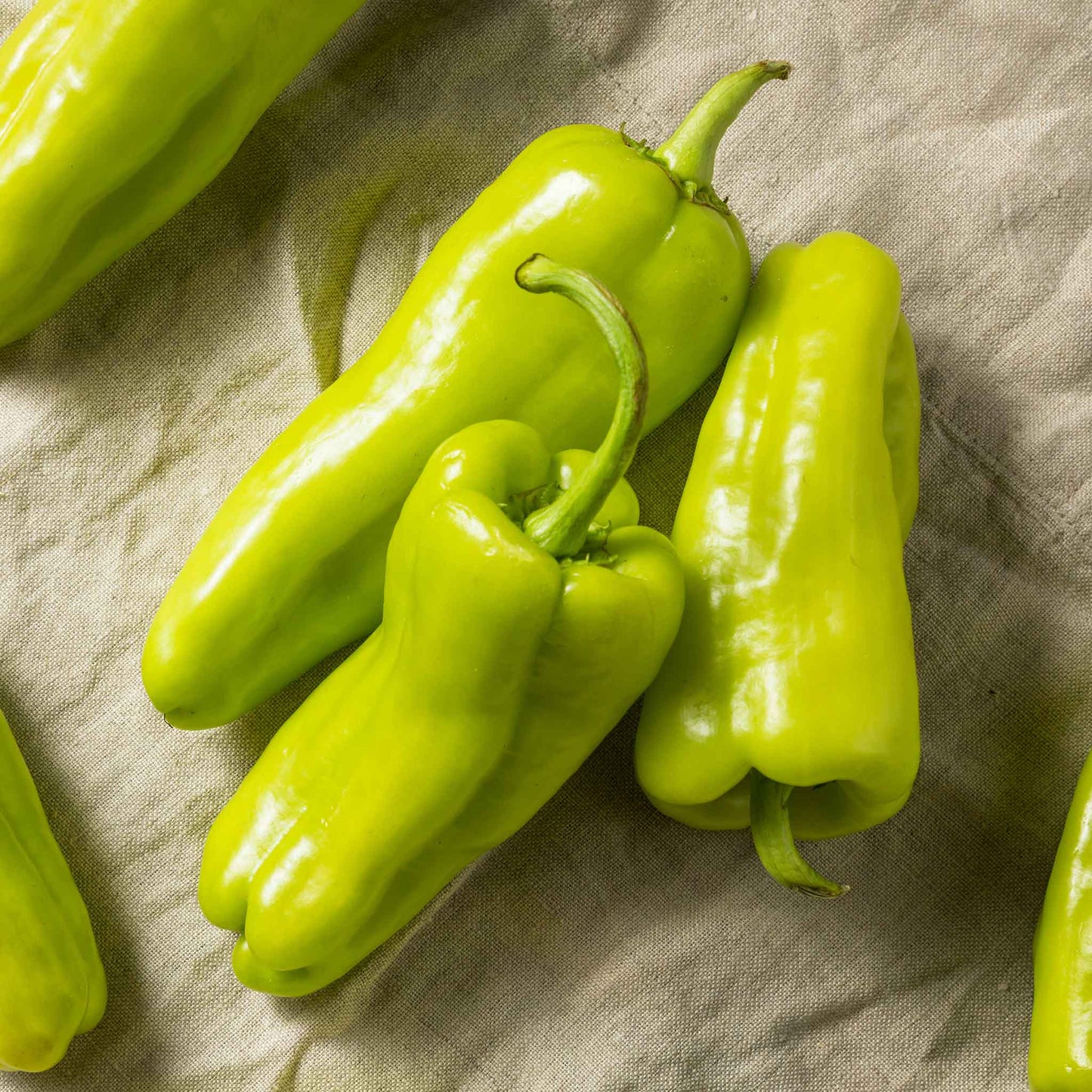 Green Cubanelle peppers with a slightly wrinkled skin and a long, tapering shape.