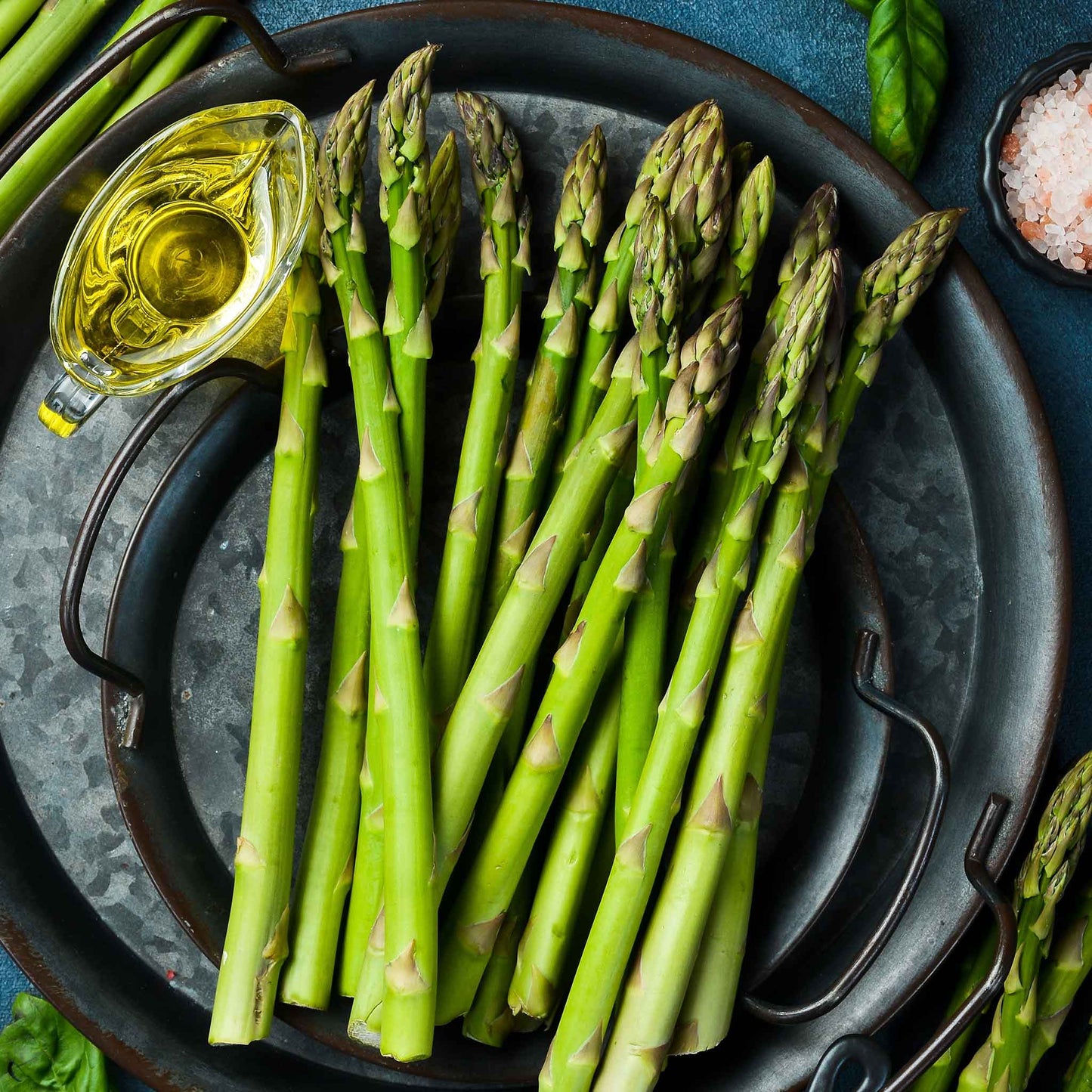 A plate of cooked mary washington asparagus with a bowl of oil for dipping.