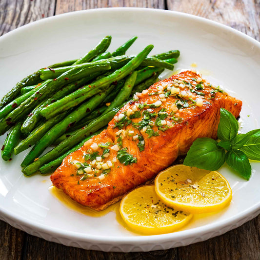 Cooked harvester beans on a plate with cooked salmon and lemon slices.