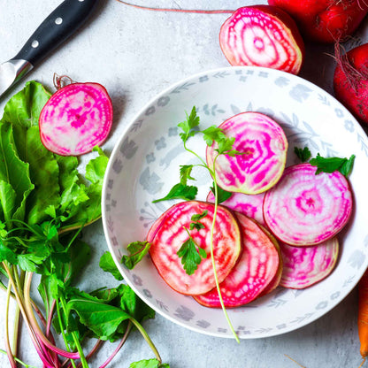 A close-up shot of several raw Chioggia beets with their striped interiors visible.