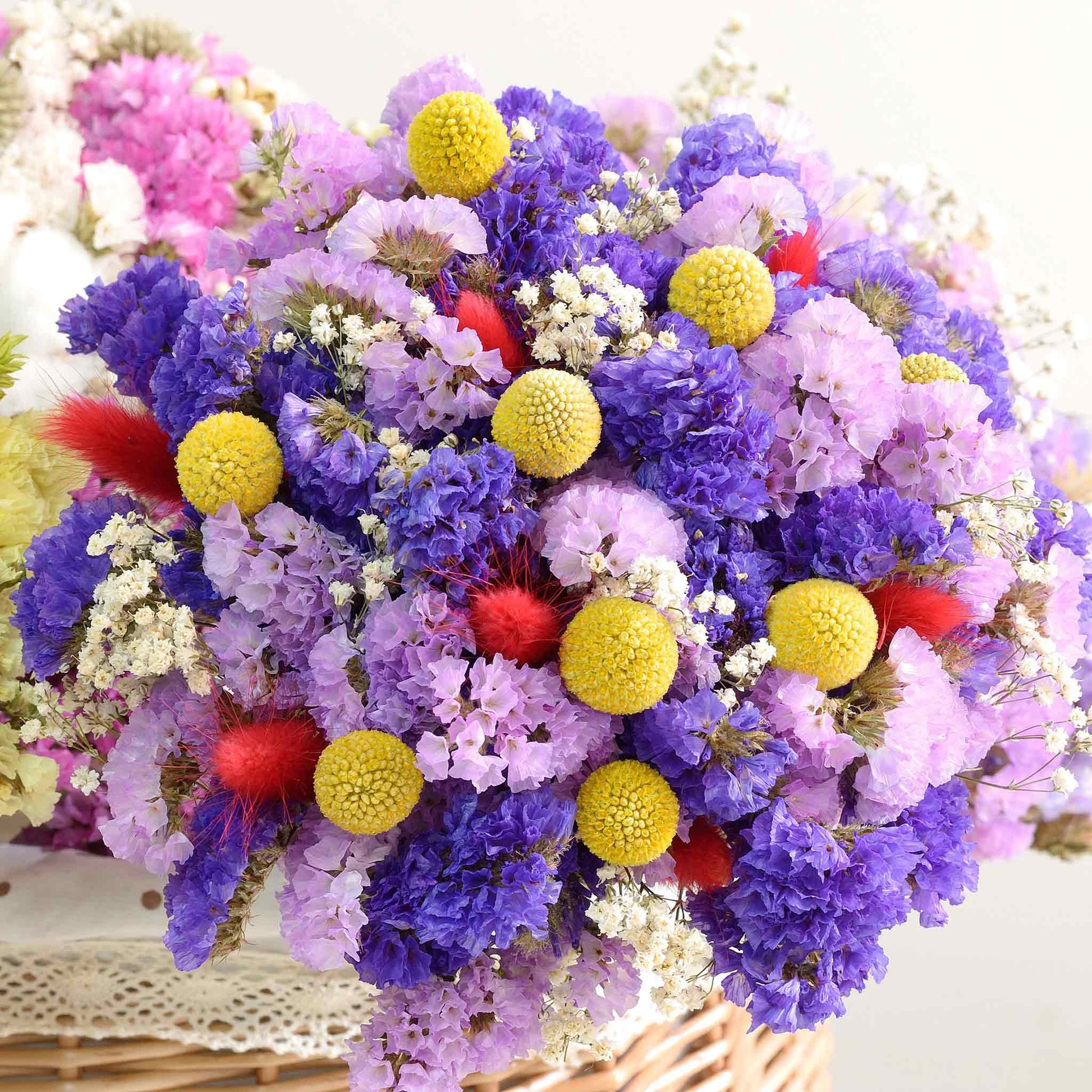 A close-up of vibrant yellow, purple and pink billy button flowers, showcasing its textured petals.