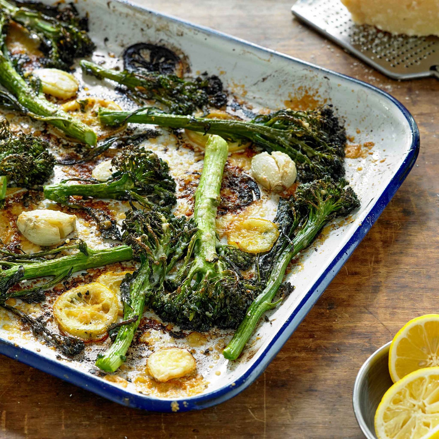 A plate of roasted spring rapini broccoli florets with asparagus and lemon slices.