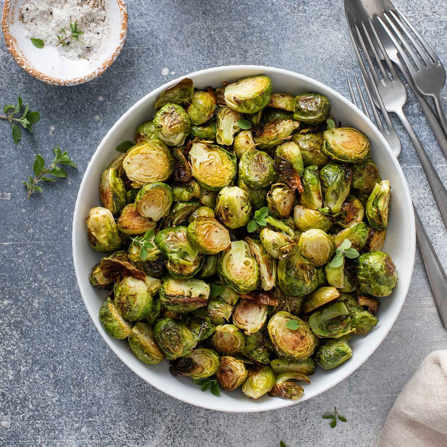 A bowl of roasted Long Island Improved brussels sprouts on a neutral background.