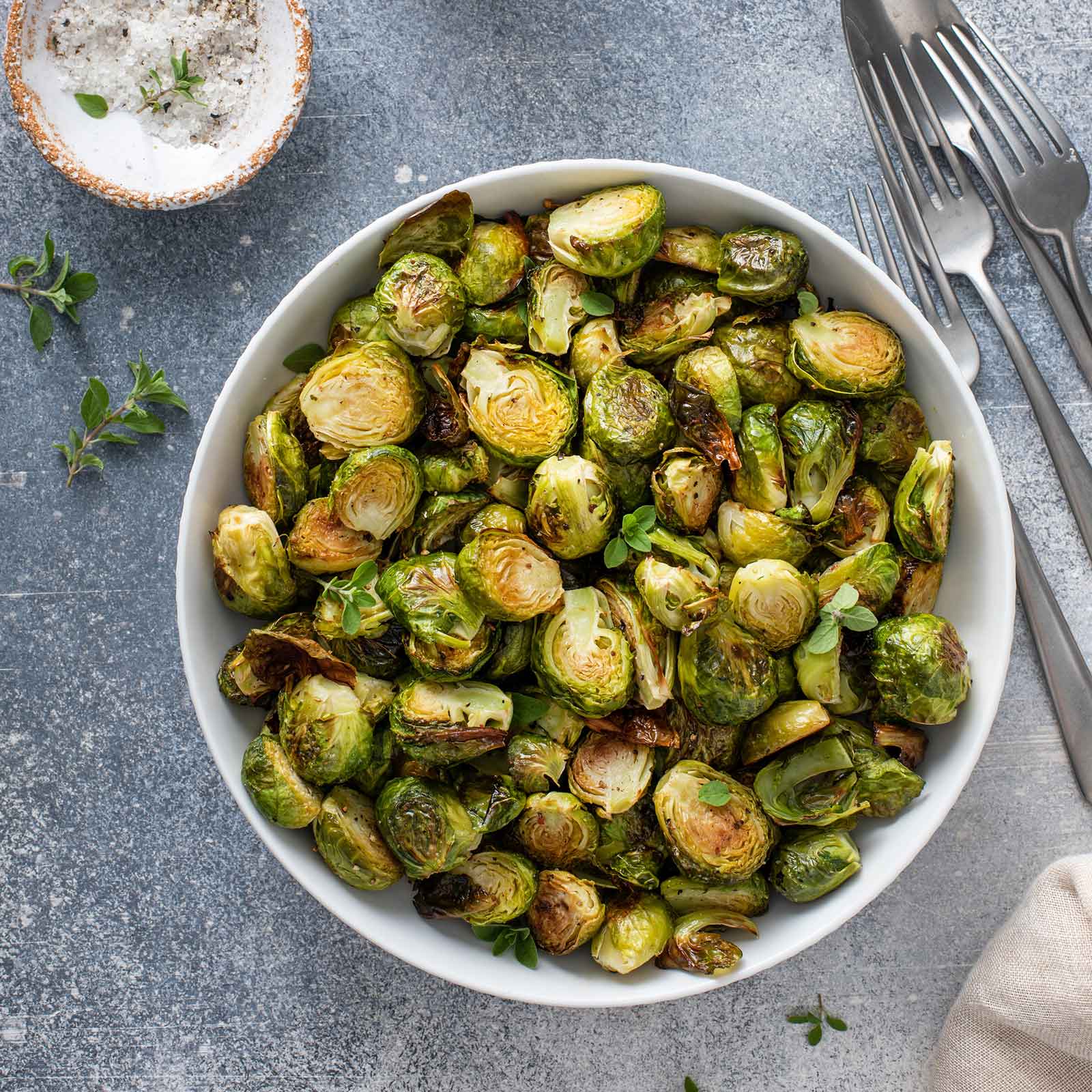 A bowl of roasted Long Island Improved brussels sprouts on a neutral background.