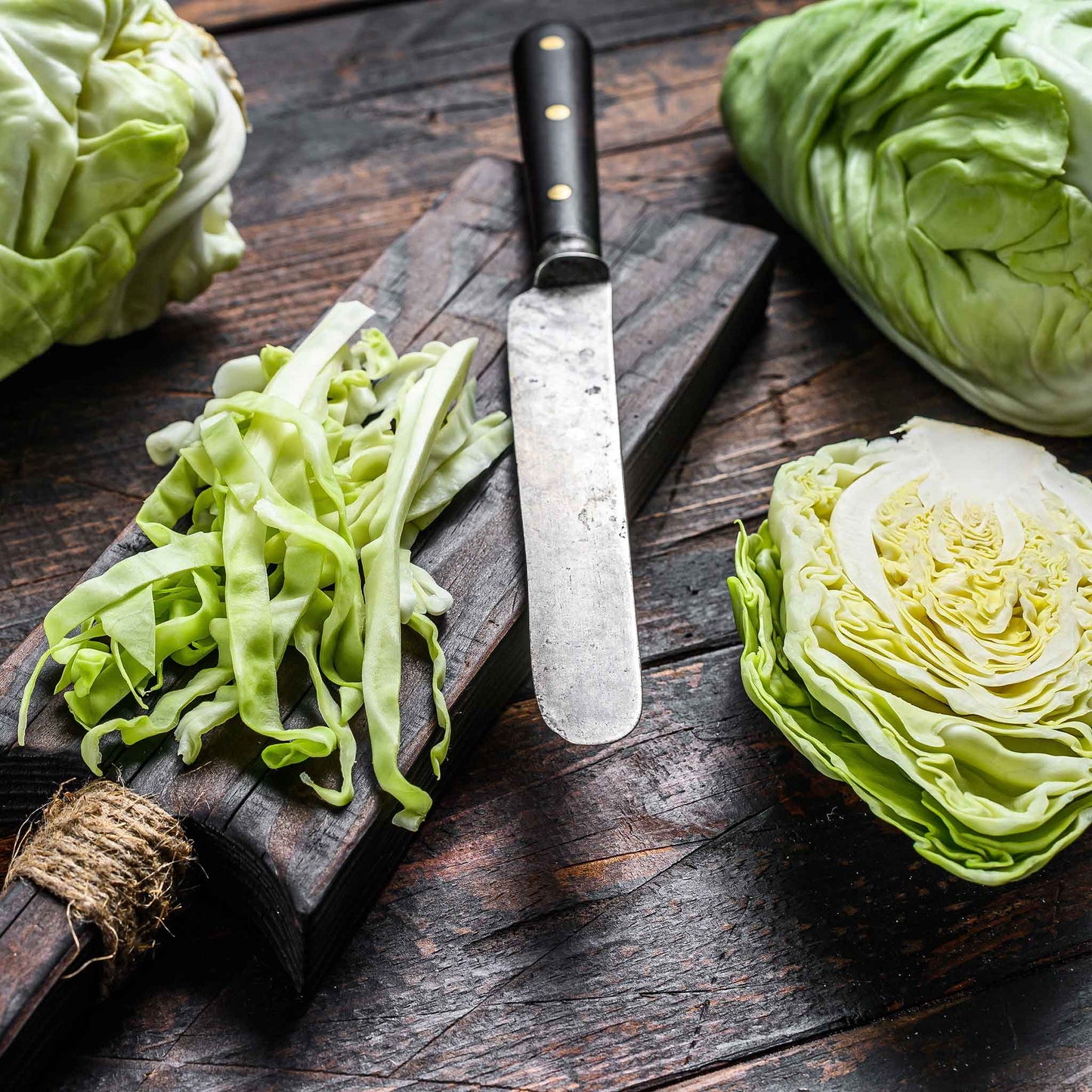 A light green, round charleston cabbage head with visible veins on its outer leaves sits on a table.