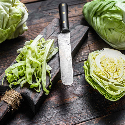 A light green, round charleston cabbage head with visible veins on its outer leaves sits on a table.