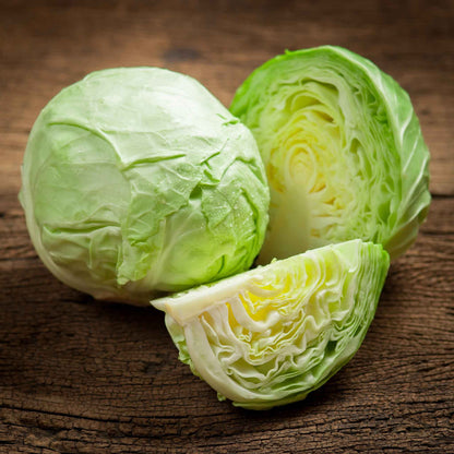 Golden Acre cabbage whole and halved on a dark background.