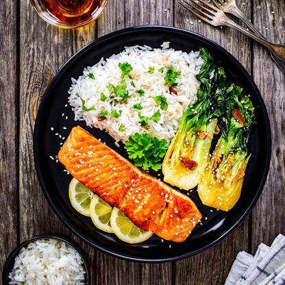 A dinner plate with roasted vegetables, rice, and cooked pak choy white stem chinese cabbage.