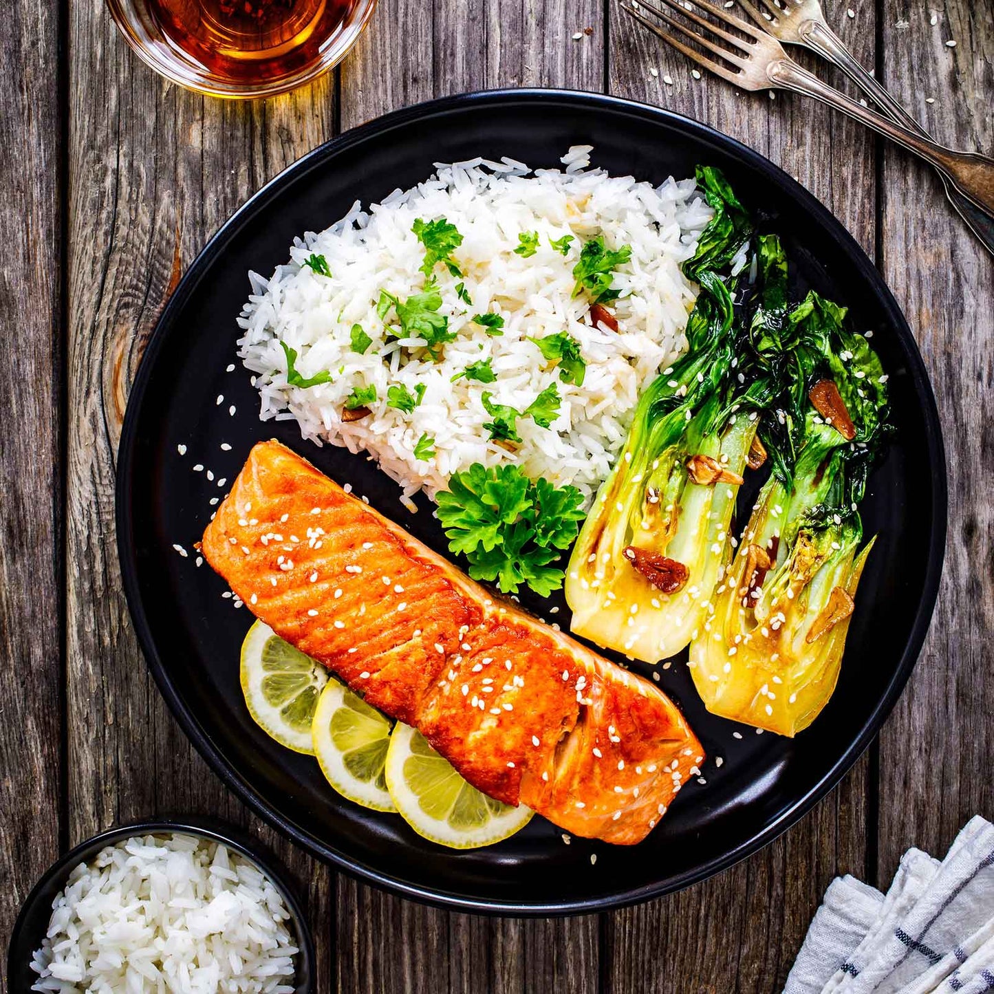 A dinner plate with roasted vegetables, rice, and cooked pak choy white stem chinese cabbage.
