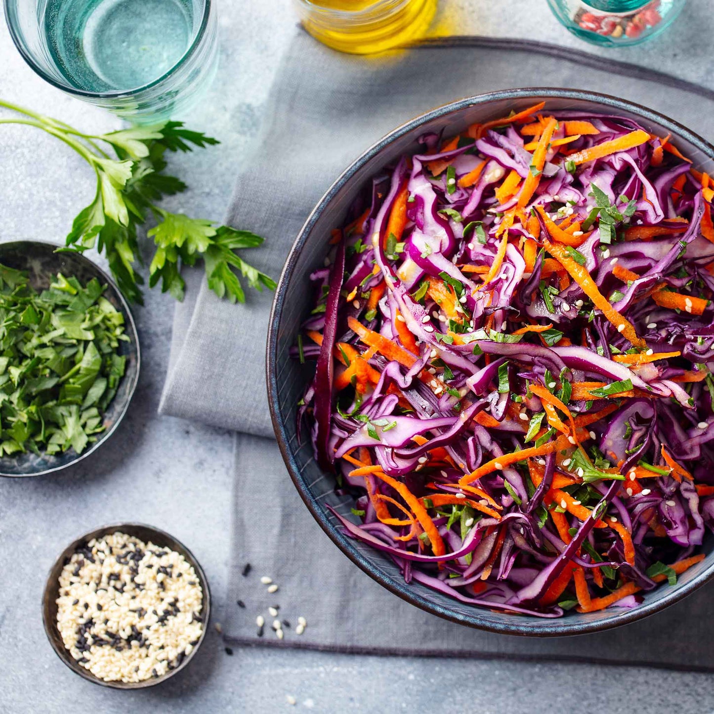 Shredded red acre cabbage in a bowl with other shredded vegetables.