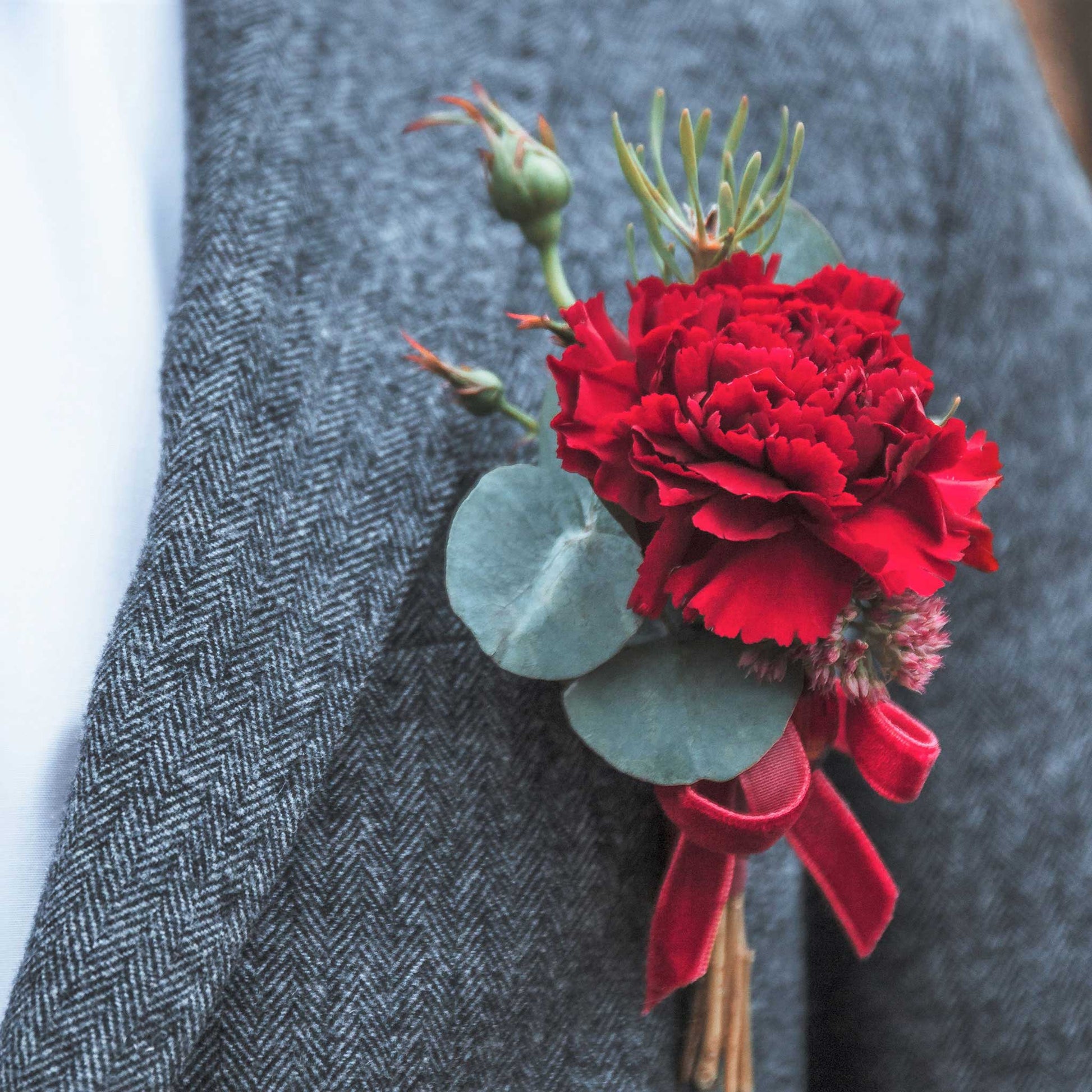 Deep red Etincellant Carnation in full bloom tied in a bouquet against a grey background.