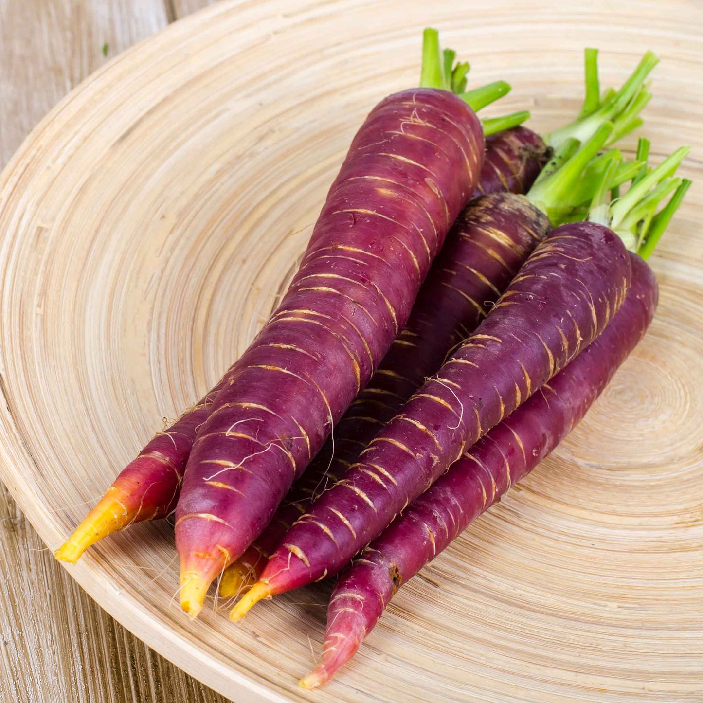 Several vibrant purple 'Cosmic Purple' carrots are shown close-up, highlighting their color and texture.