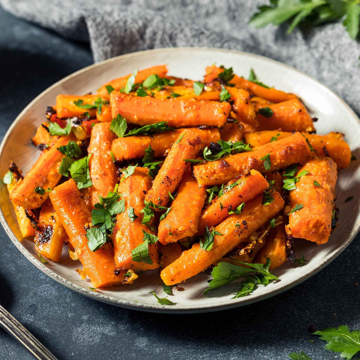 A plate of roased little finger carrots garnished with parsley.