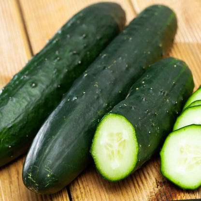 Some Poinsett 76 Cucumbers with dark skin on a wooden surface.