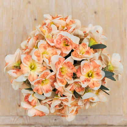 An overhead view of a bouquet of Sunny Girlfriend daffodil flowers in a rustic setting.