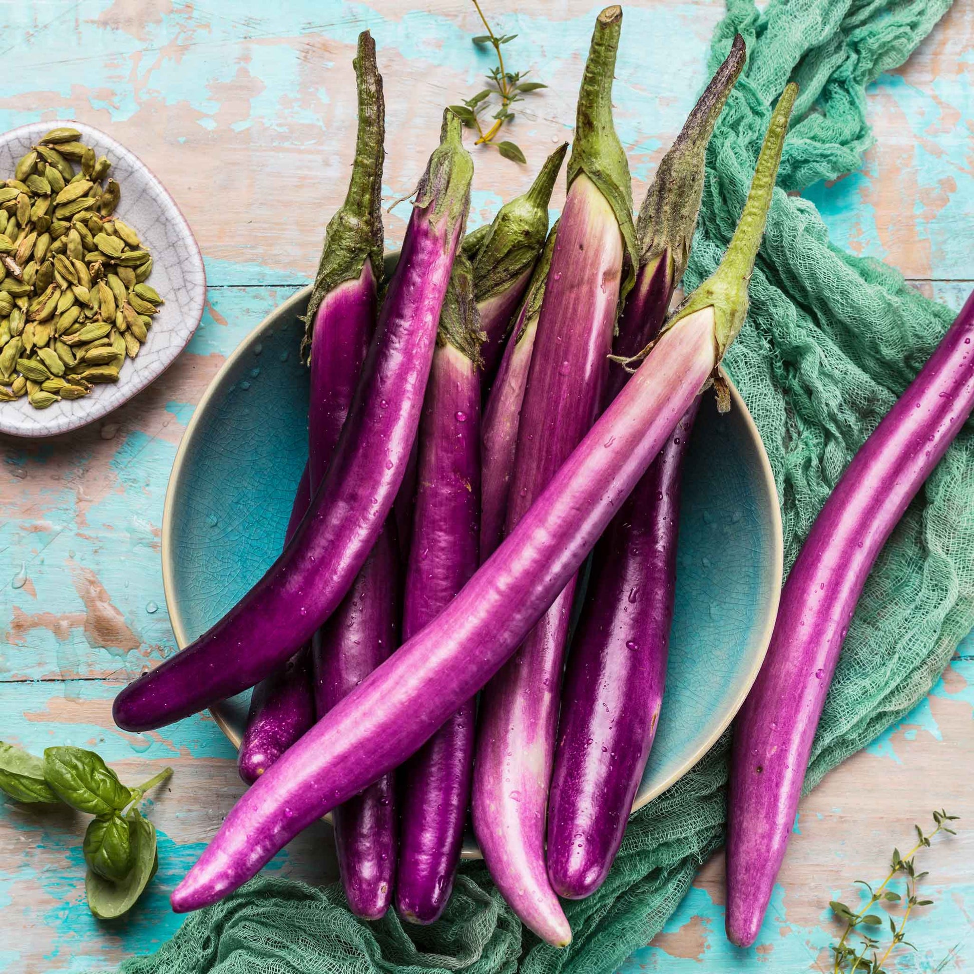 A plate of Long Asian eggplants with light purple skin and elongated bodies.