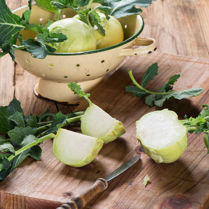 A close-up shot of a white kohlrabi bulb cut open showing the white interior on a cutting board.