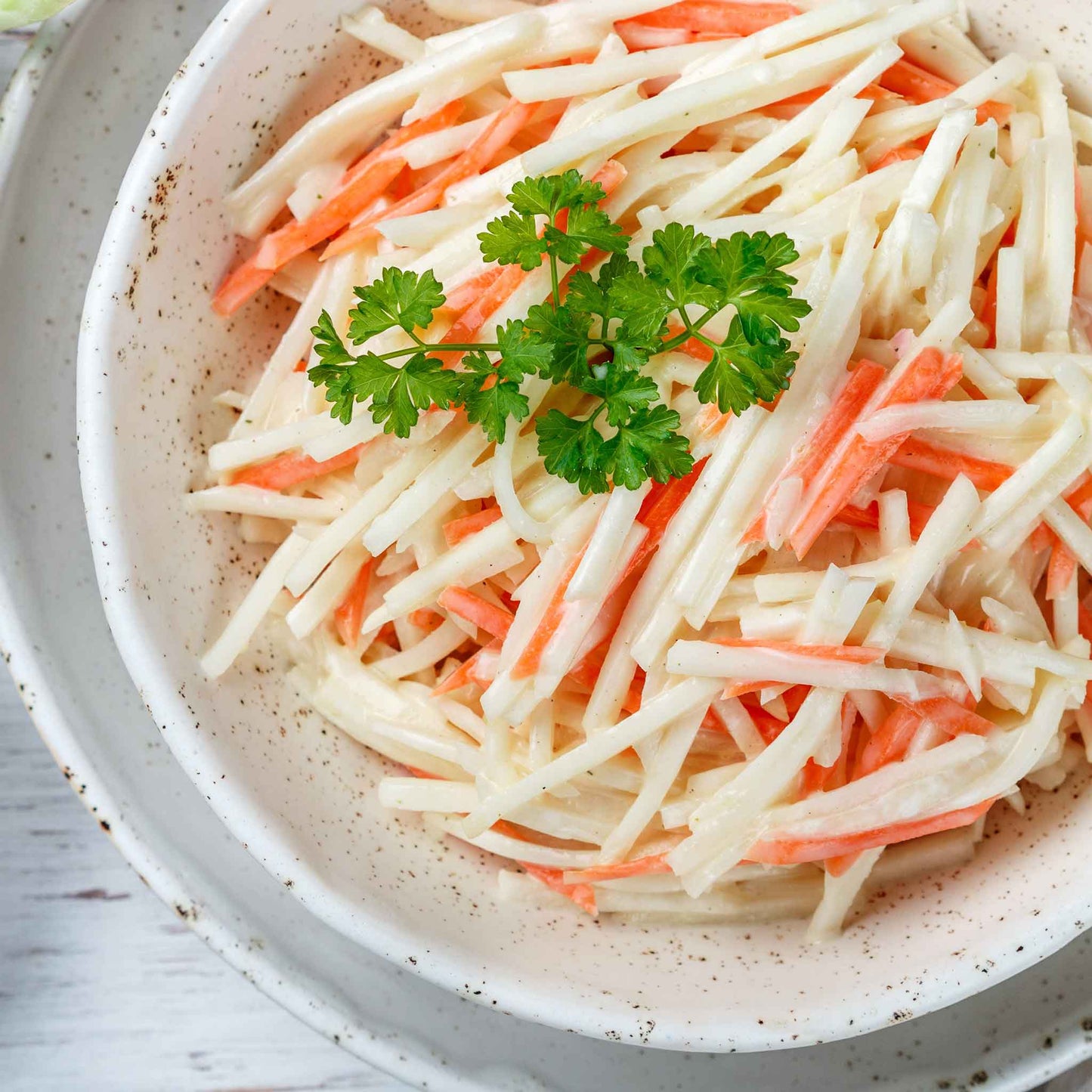 Sliced White Vienna kohlrabi on a plate with a sliced orange vegetable ready to eat.