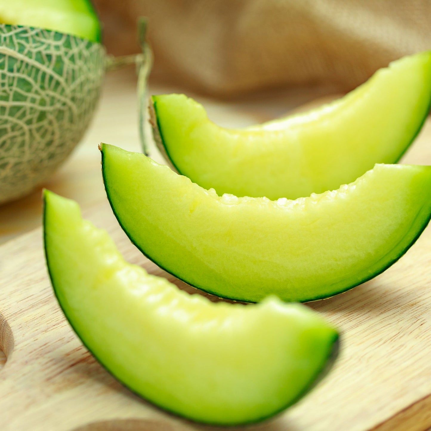 A ripe, green-fleshed Rocky Ford melon, perfectly sliced and ready to eat, on a rustic surface.