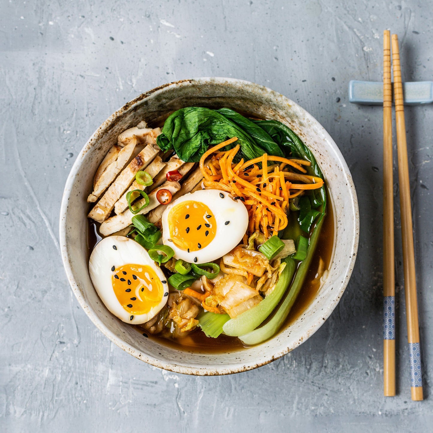 A bowl of food with Tatsoi mustard leaves on a light surface.