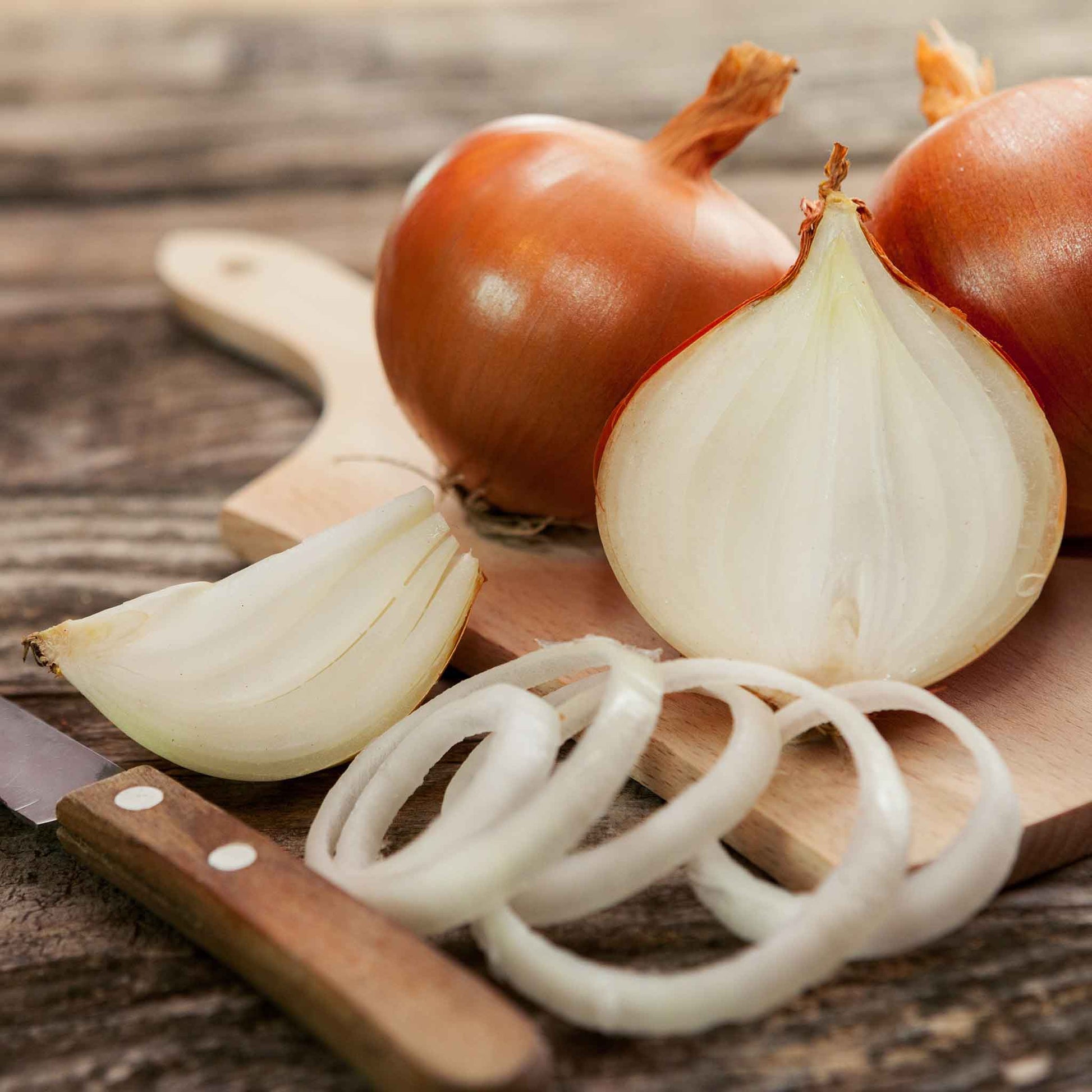 Close-up of a bunch of candy onions with thin, papery, golden-brown skins and sliced rings.