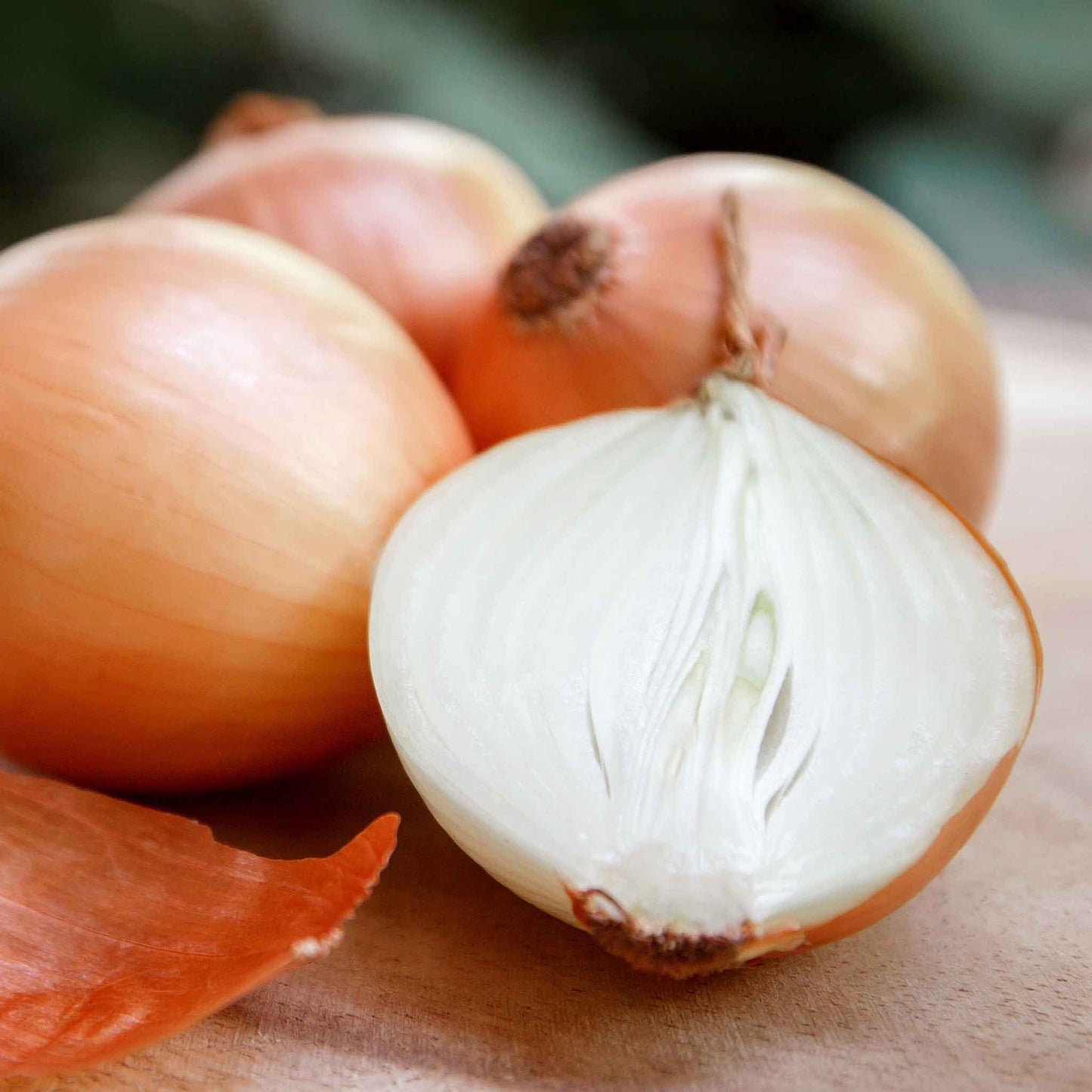 A close-up shot of several large, yellow sweet Spanish onions, showcasing their golden-brown skin and round shape.