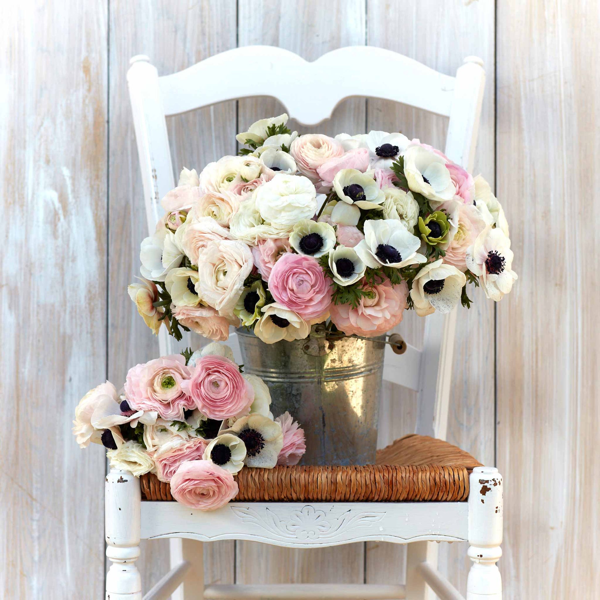A bouquet of Paris in Spring anemone and ranunculus flowers on a white chair.