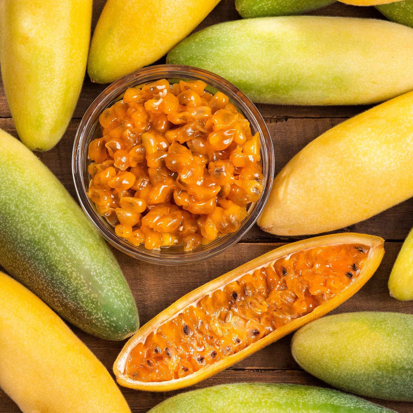 Passiflora banana passion fruit ripe yellow-green fruits with orange flesh on a plain backdrop.