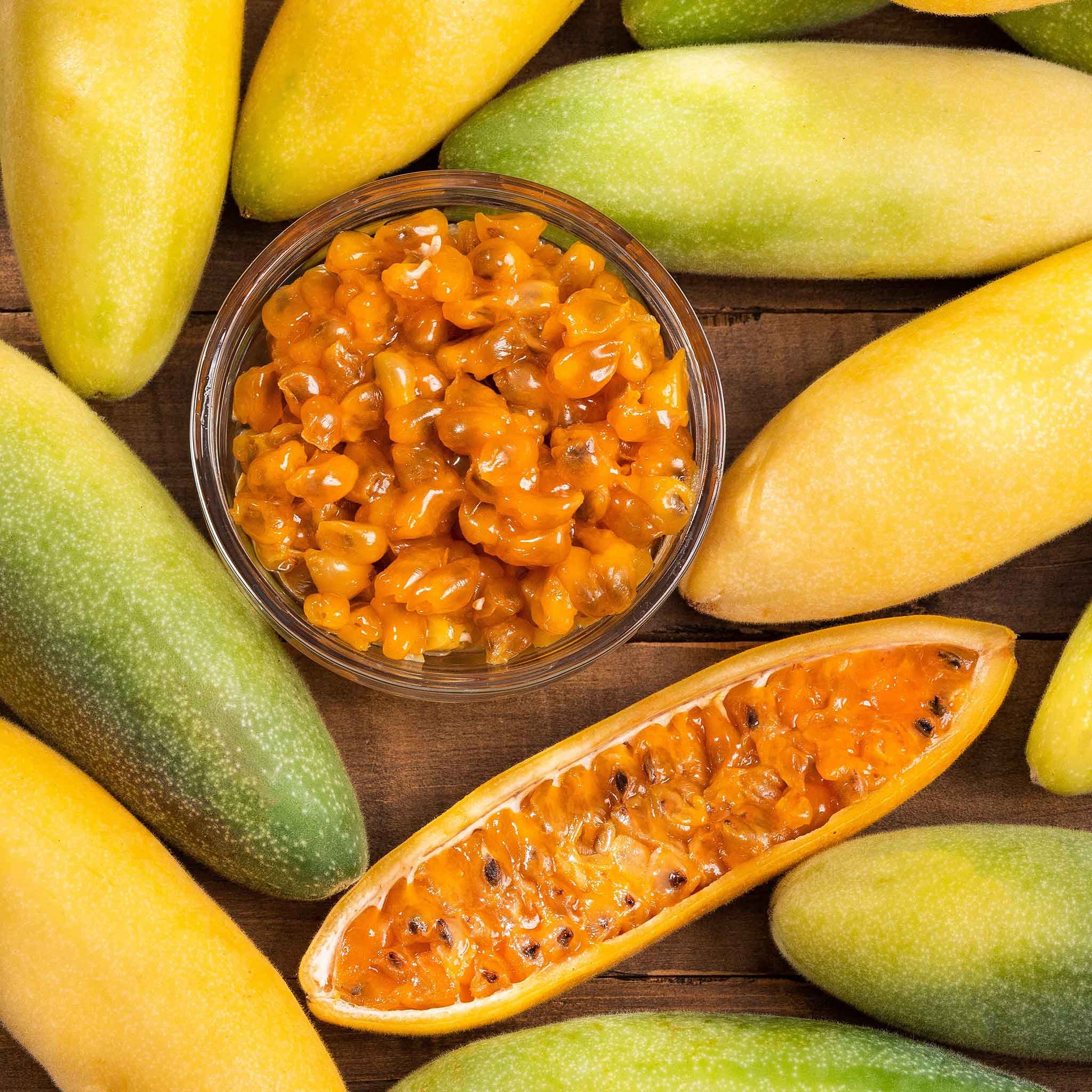Passiflora banana passion fruit ripe yellow-green fruits with orange flesh on a plain backdrop.
