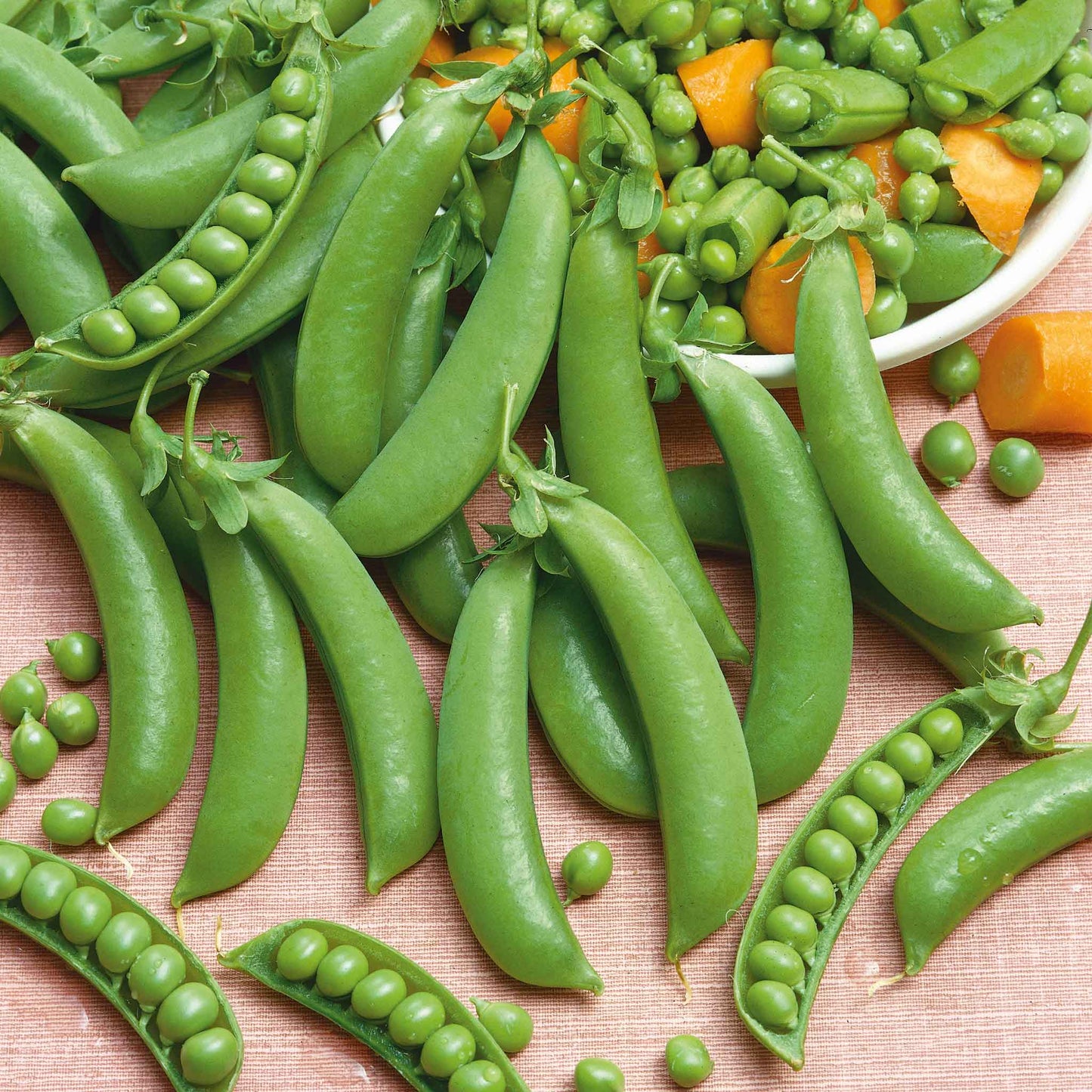 Close-up of vibrant green Sugar Ann pea pods with stems on a wooden surface.