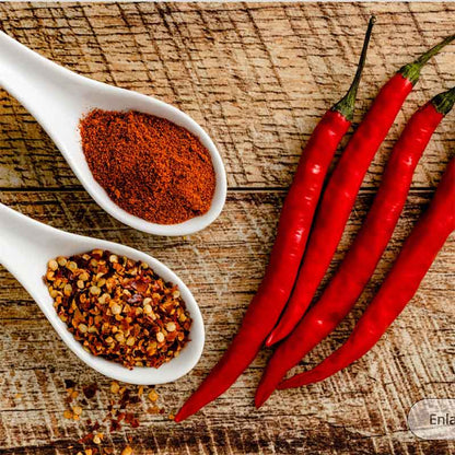 Several slender, Cayenne Long Red Thin peppers are shown with pepper flakes and ground peppers.