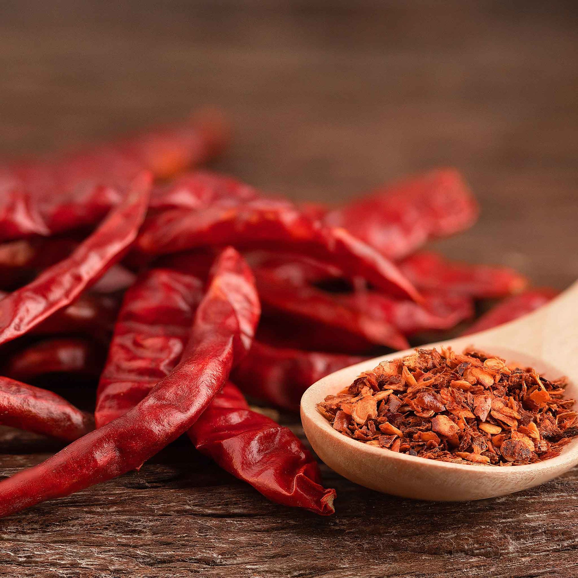 Several slender, Cayenne Long Red Thin peppers are shown with pepper flakes peppers.