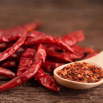 Several slender, Cayenne Long Red Thin peppers are shown with pepper flakes peppers.