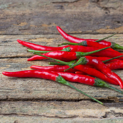 Several dried red chile de arbol peppers are bundled together against a rustic background.