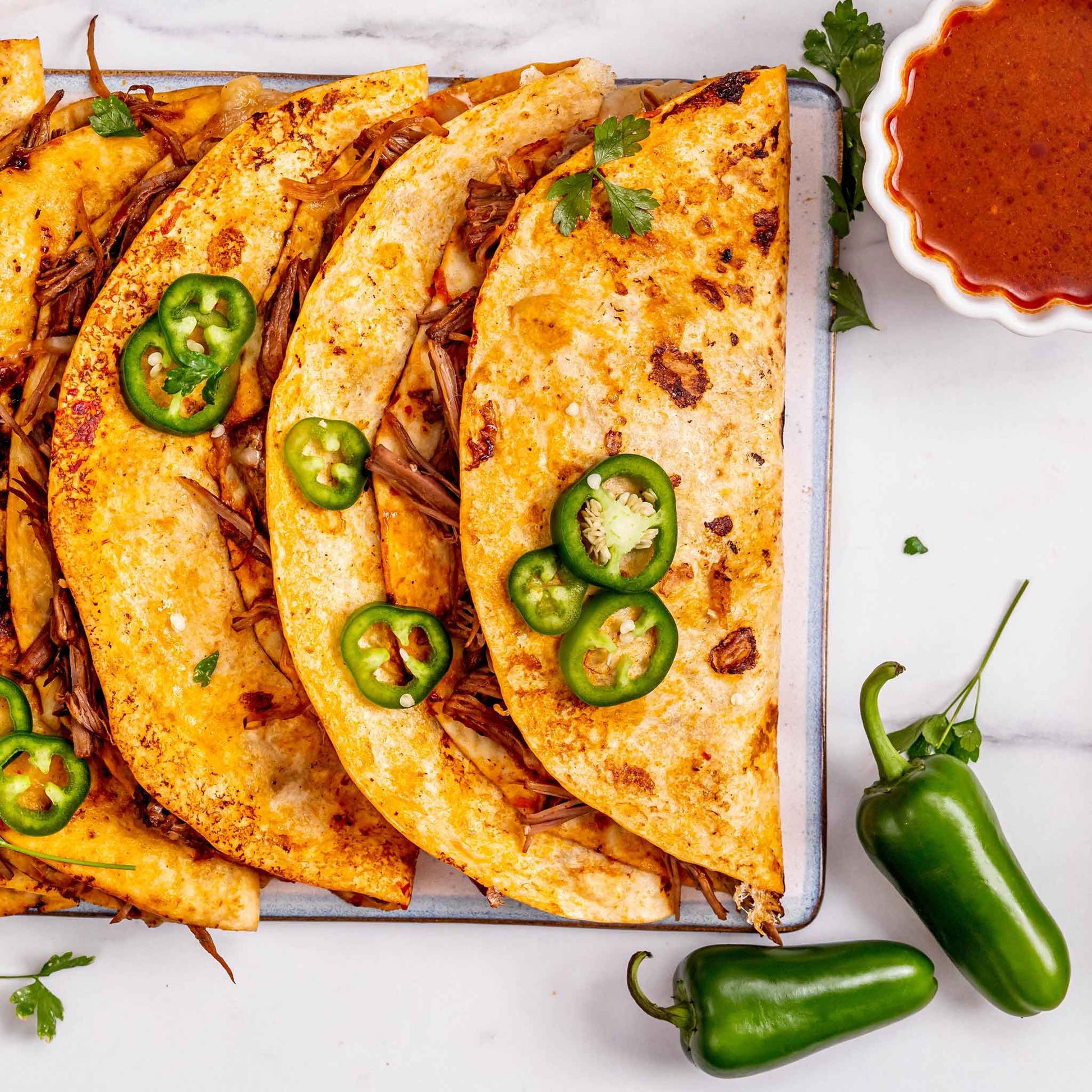 Quesadillas displayed on a board on top of a wooden surface using Jalapeno Early peppers.