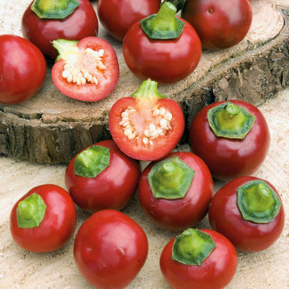 Several Red Cherry Sweet peppers with squat red bodies and green stems.