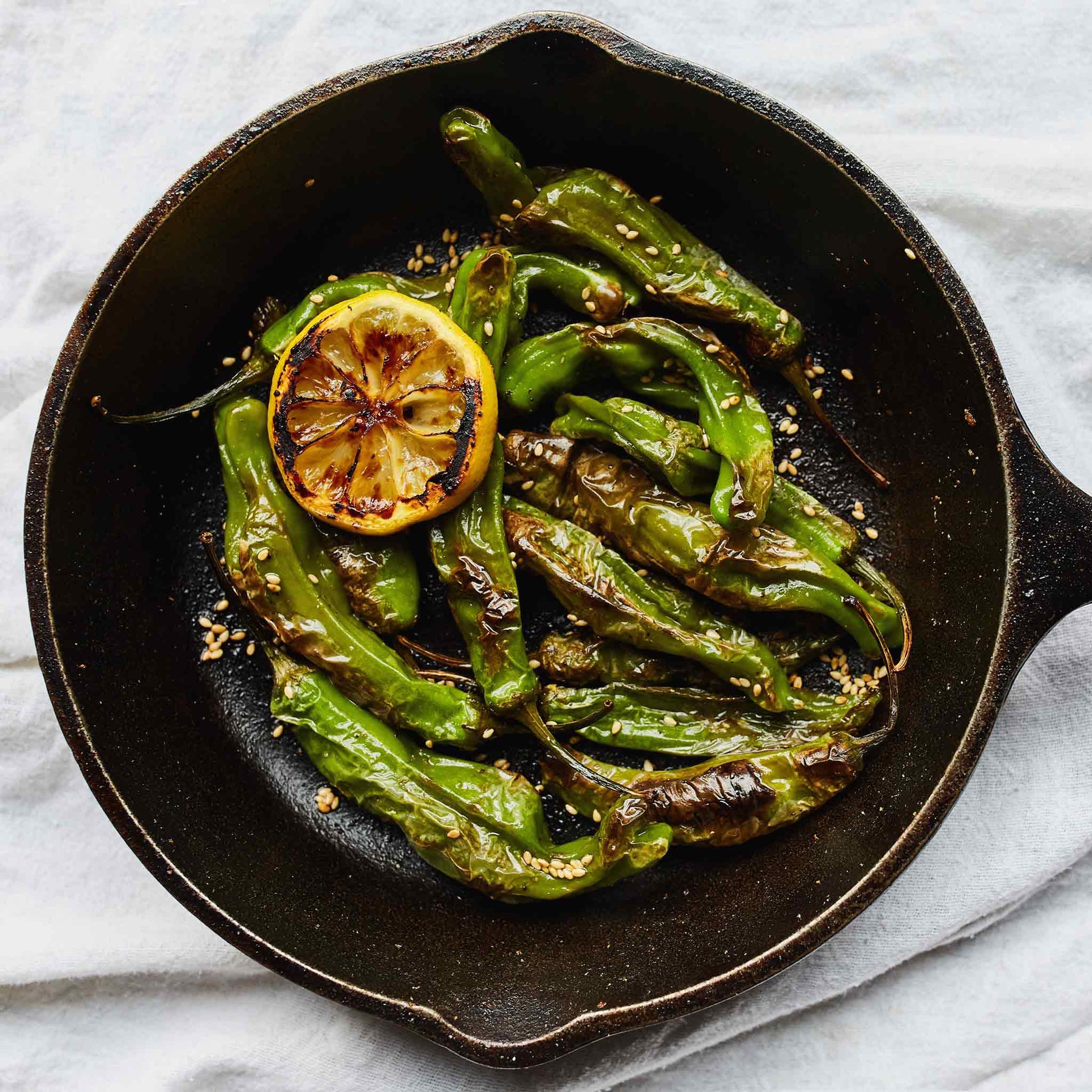 Sauteed Shishito peppers with a lemon ready for eating.