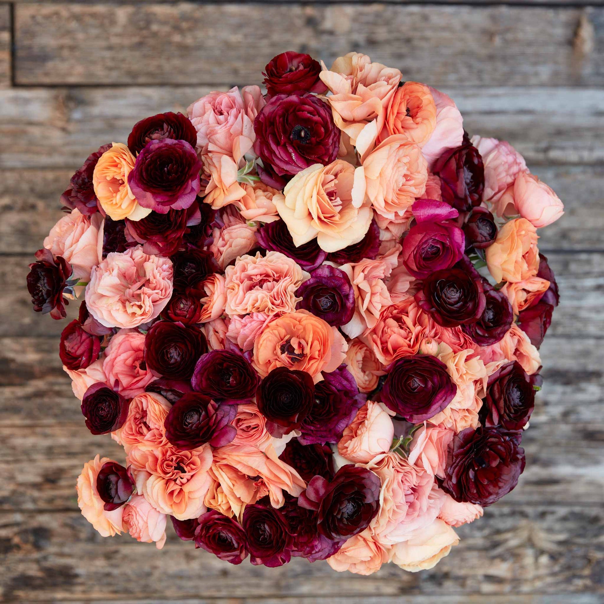 Deep red and dark pink ranunculus princess bride mix bouquet on a natural backdrop