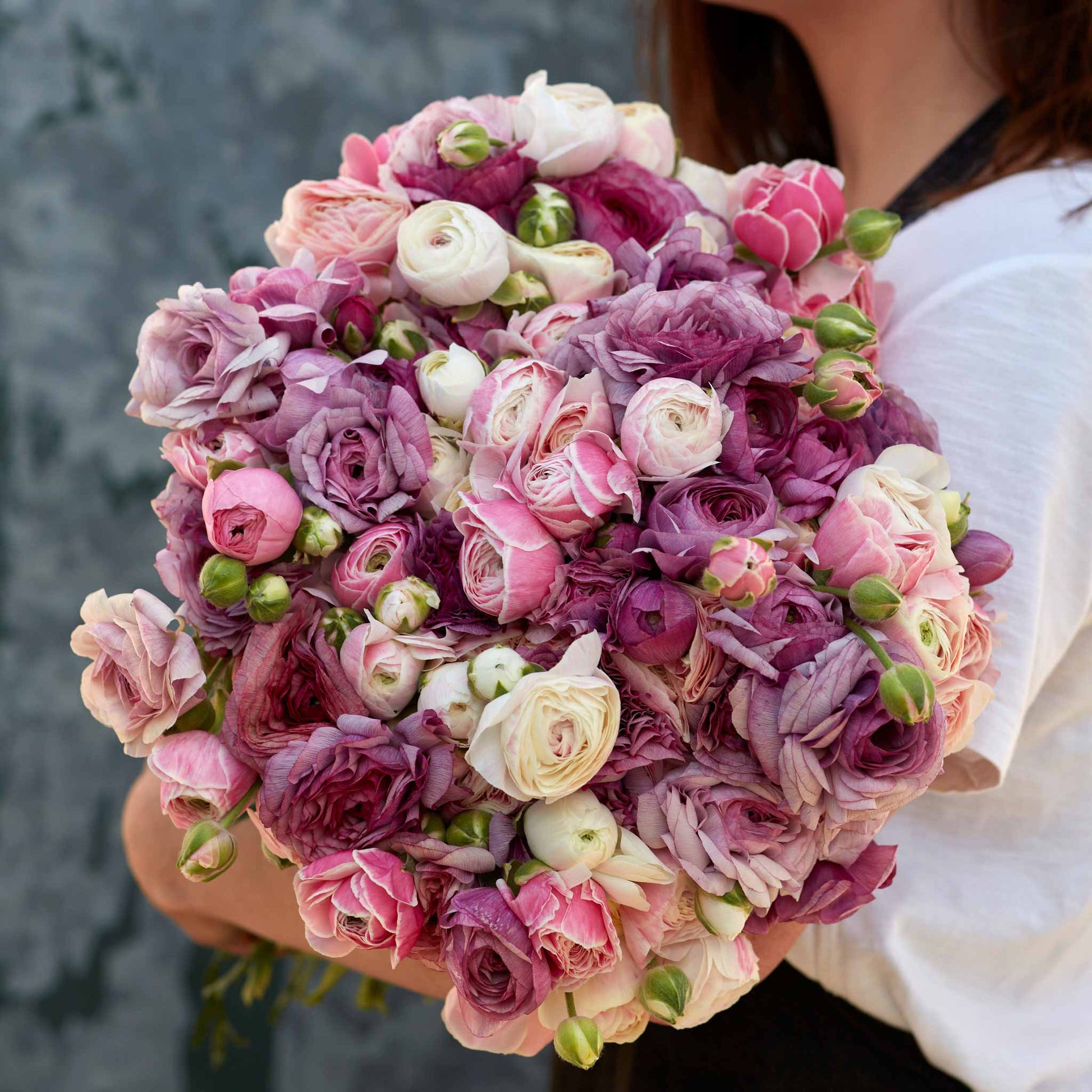 Deep pink secret garden mix ranunculus bouquet on a natural warm backdrop