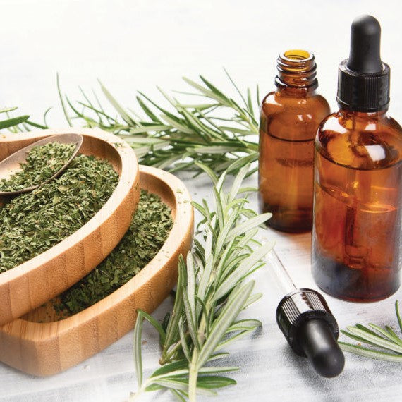 Freshly harvested rosemary next to bottles of rosemary oil and crushed rosemary.