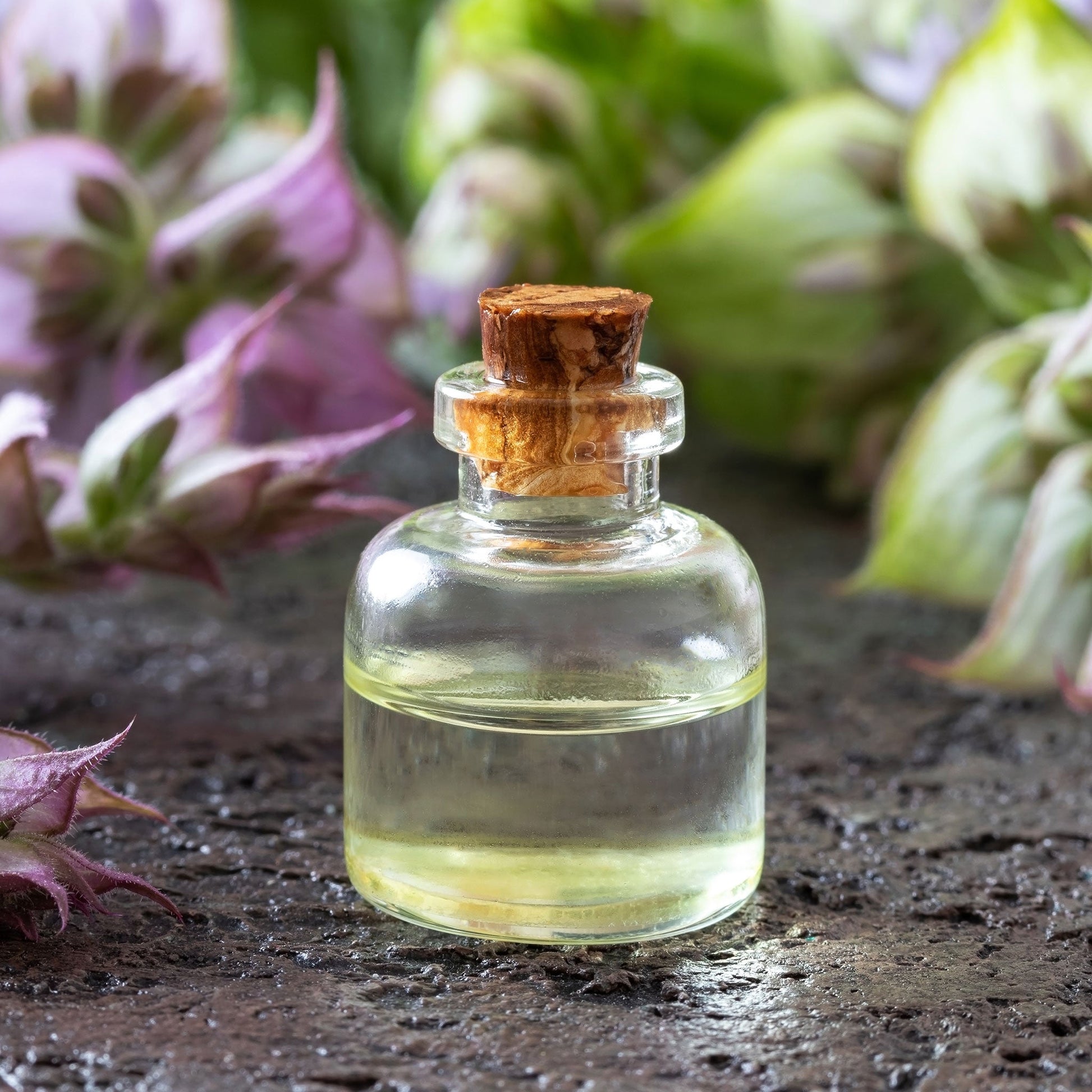 Clary Sage Pink Sundae small oil bottle against a blurred purple flower background