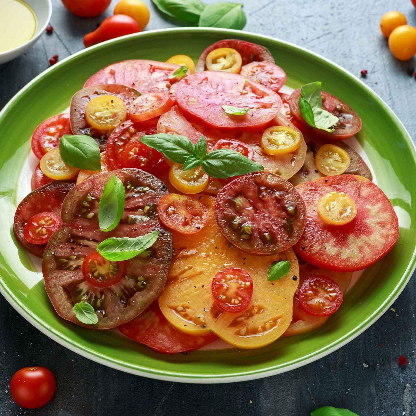 Slices of Black Brandywine tomato with other tomatoes, shown on a plate.