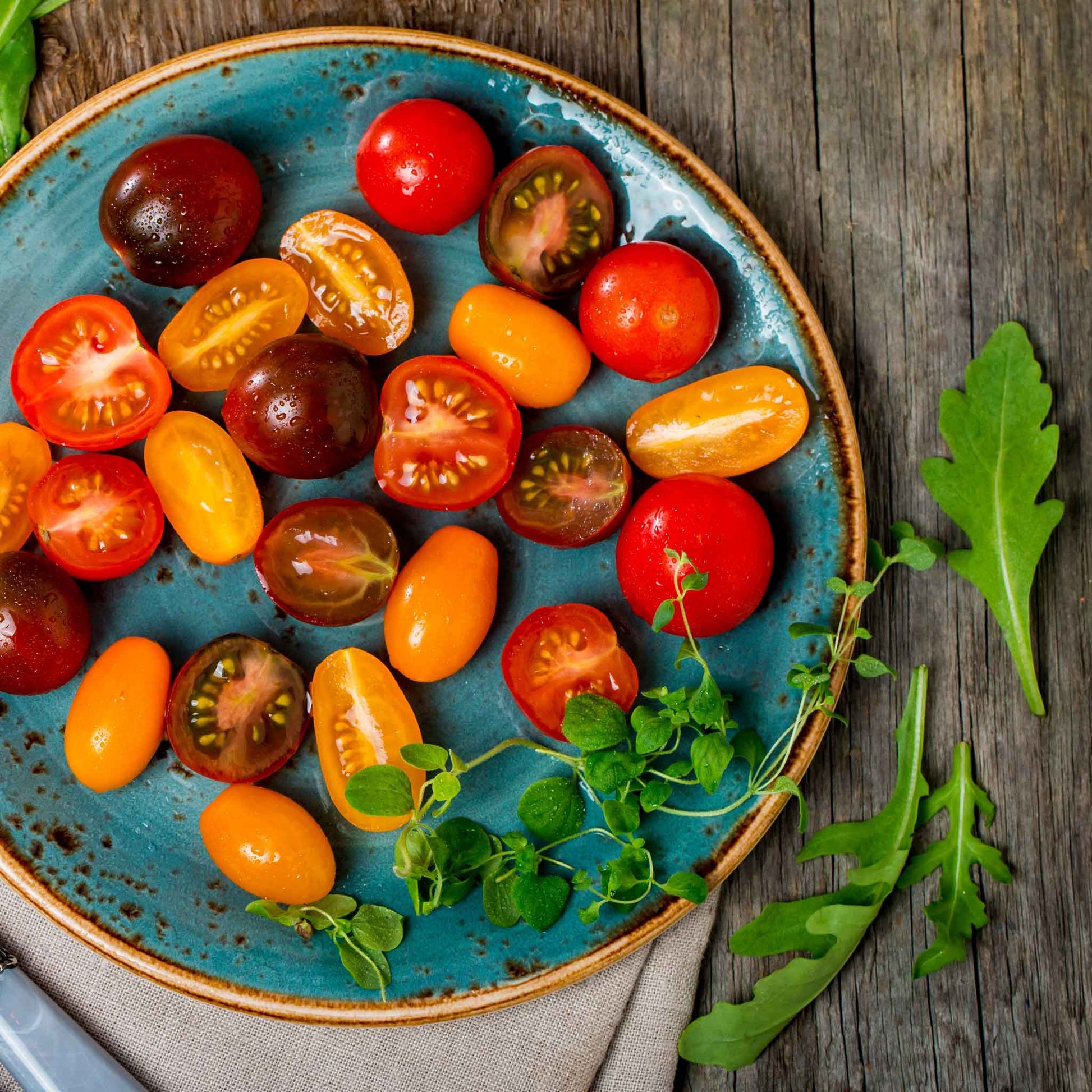 A Rainbow Cherry Mixture assortment of tomatoes sliced on a plate.